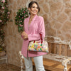 Woman in pink blazer and white jeans holding our Nicole Lee Dreams Blossom dome handbag in a modern background.