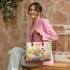 Woman sitting on a bench wearing a pink blazer smiling holding our Nicole Lee Dreams Blossom Tote in a modern background.