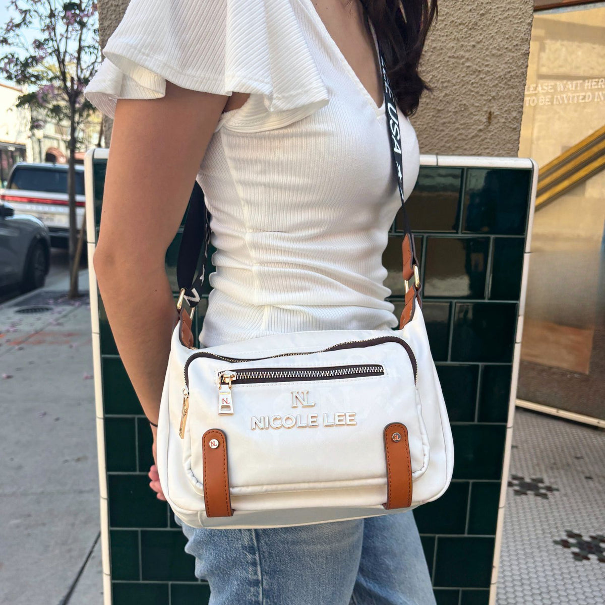 WOMEN IN A WHITE TOP AND BLUE JEANS USING OUR MARGOT SHOULDER BAG IN WHITE.