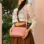 WOMEN IN A IVORY CROCKET CROP TOP AND BROWN SKIRT, HOLDING OUR PINK GRACIE CROSSBODY. 