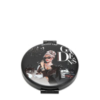 LADY IN BLACK , SHE IS WEARING ABLACK V NECK DRESS AND SUNGLASSES. SITTING IN A TABLE WITH A CUP OF COFFEE AND HAS HER HANDBAG ON THE TABLE. IN THE BACKGROUND THERE IS A CHANDELIER AND SOME NICOLE LEE SHOPPING BAGS