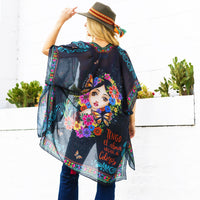 Woman in black top, blue jeans and green hat wearing our Nicole Lee Kimono Akiko la Belleza design.