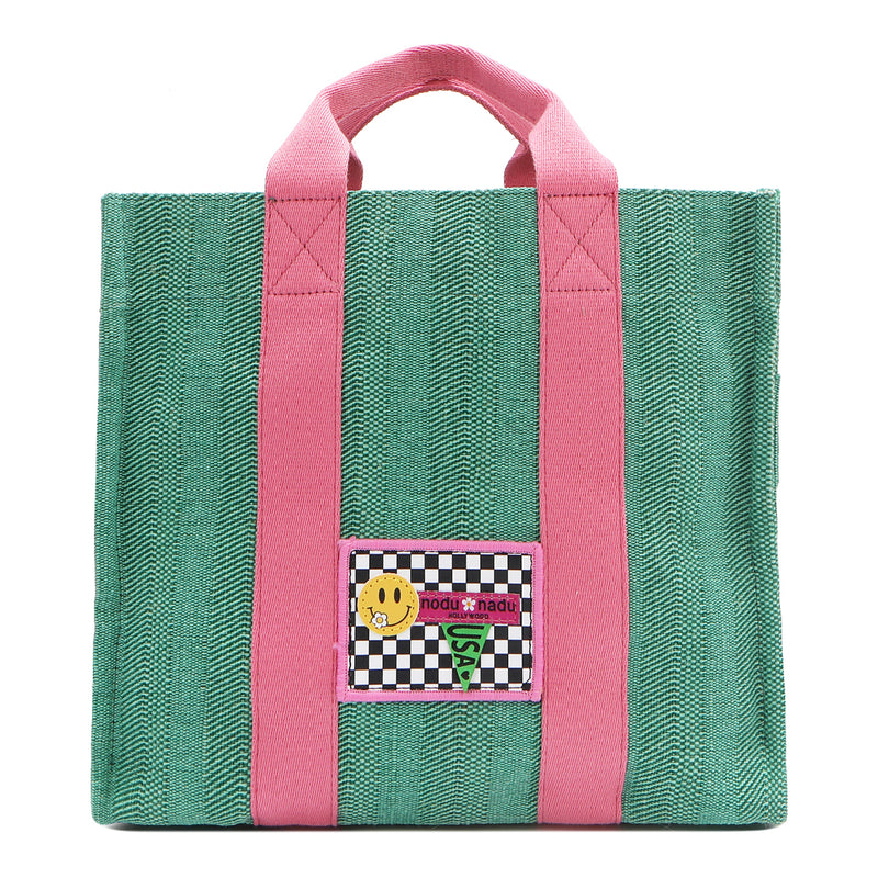 Your must-have carryall for school, weekends, and everything in between! Designed with a soft, relaxed silhouette, the Nodu Nadu Sawyer in Green offers plenty of space to keep notebooks and loose essentials effortlessly organized—so you're always ready to grab and go! Light green-colored canvas paired with baby pink strap accents. 