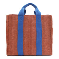 Back of the Nodu Nadu Sawyer Bag in Orange. Orange/sienna brown-colored canvas accented with bold electric blue straps for a pop of trendy color and vibrance. Rectangular silhouette provides a sense of classic timelessness so you can dress up or dress down this everyday style. 