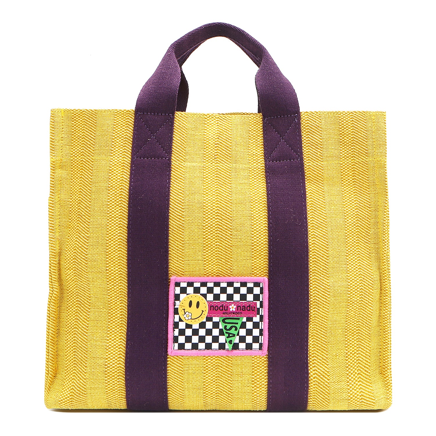 Your must-have carryall for school, weekends, and everything in between! Designed with a soft, relaxed silhouette, the Nodu Nadu Sawyer in Yellow offers plenty of space to keep notebooks and loose essentials effortlessly organized—so you're always ready to grab and go! Sunny yellow canvas paired with eggplant purple strap accents. 