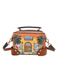 Our Sun and Sand Crossbody bag with a tropical design featuring palm trees and a beach scene set on a white background.