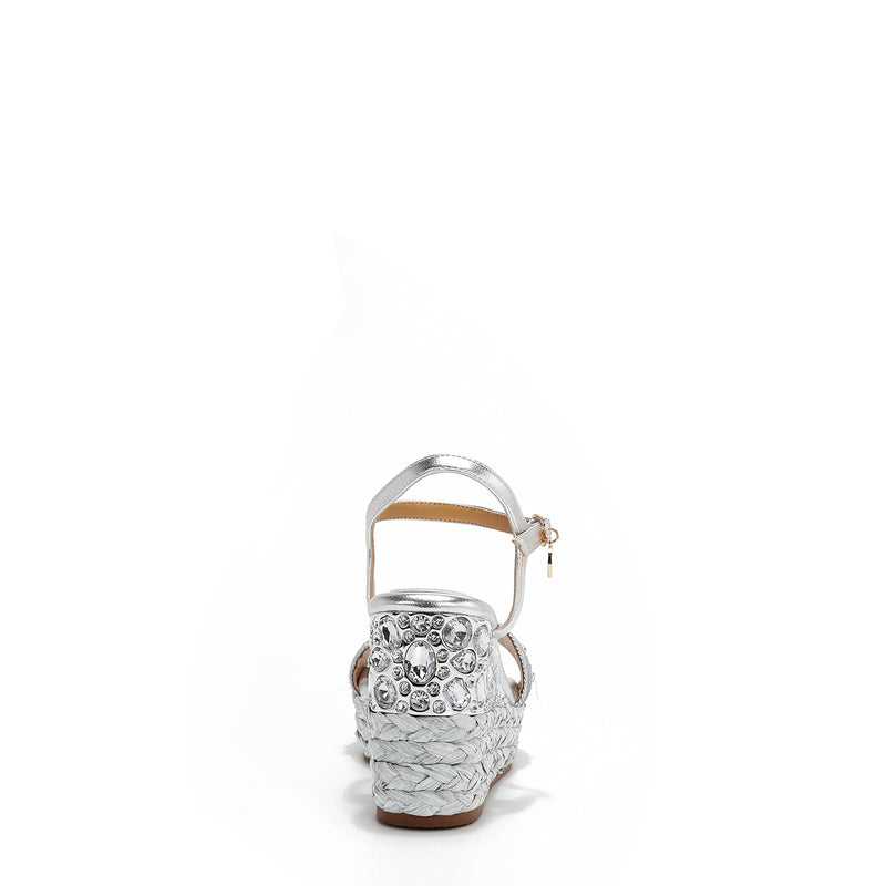 The platform  wedge is adorned with silver rhinestones and  braid detailing.