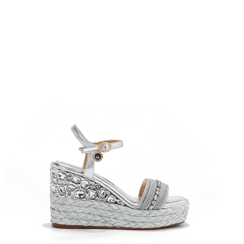Kali Espadrille Wedge sandal in Silver.  Fitted with 1 adjustable buckle. The buckle has a small Nicole Lee Charm.The wedge is adorned with rhinestones and  braid detailing.