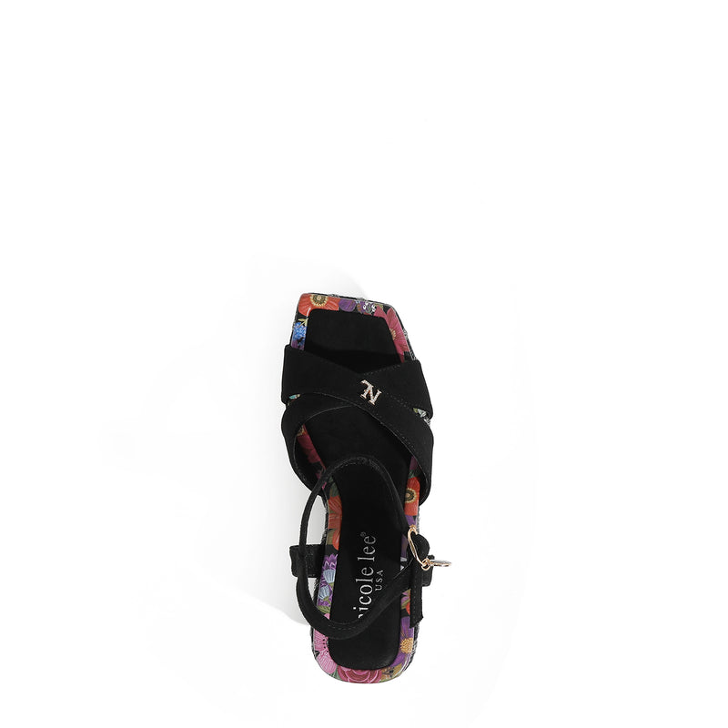 THE SANDAL FROM A VIEW FROM ABOVE. THE CRISSCROSS STRAPS WITH THE NL INITIALS IN THE MIDDLE. THE BLACK INSOLE WITH FLORAL PRINT ON THE EDGES.